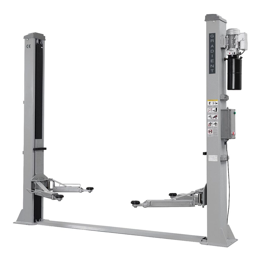 Frontale Gesamtansicht einer grauen Zwei-Säulen-Kfz-Hebebühne mit Bodenquertraverse, höhenverstellbaren Tragar­men und integrierter Steuereinheit an der rechten Säule.