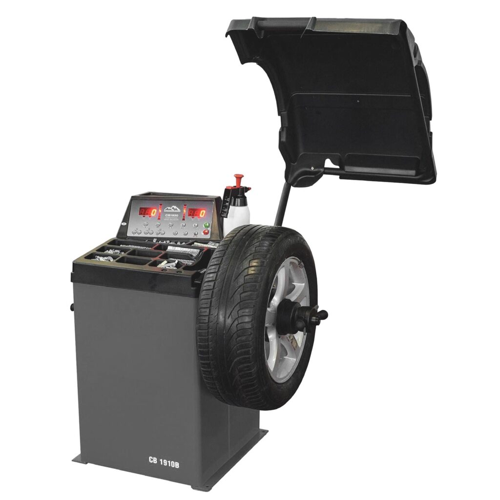 Pkw-Radauswuchtmaschine mit montiertem Autofelgenrad, digitalem Display, integrierter Ablage für Auswuchtgewichte und hochgeklappter Schutzhaube.