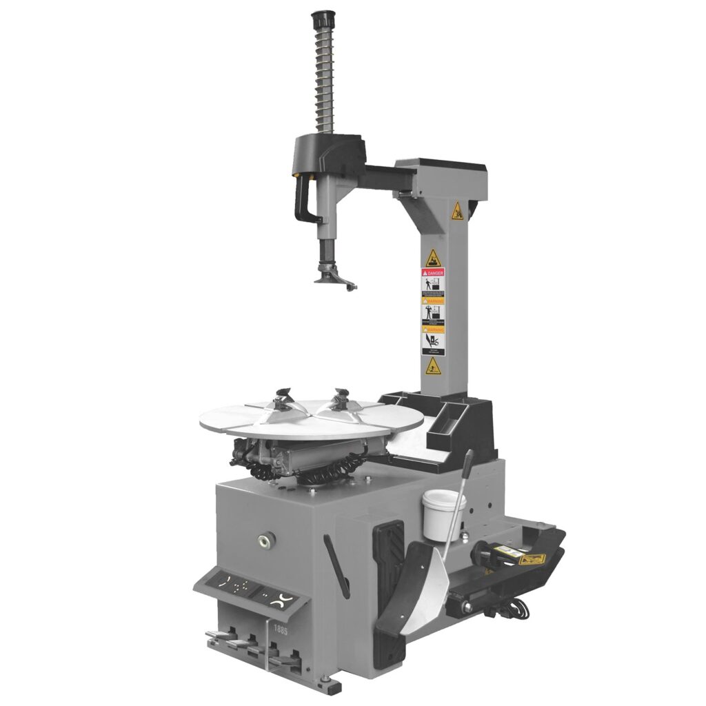 Reifenmontiermaschine mit vertikalem Montierarm, gefederter Abdrückeinheit, rotierendem Spann­teller mit vier Spannklauen, seitlicher Abdrückschaufel, Pedalsteuerung und integrierten Sicherheitsaufklebern.